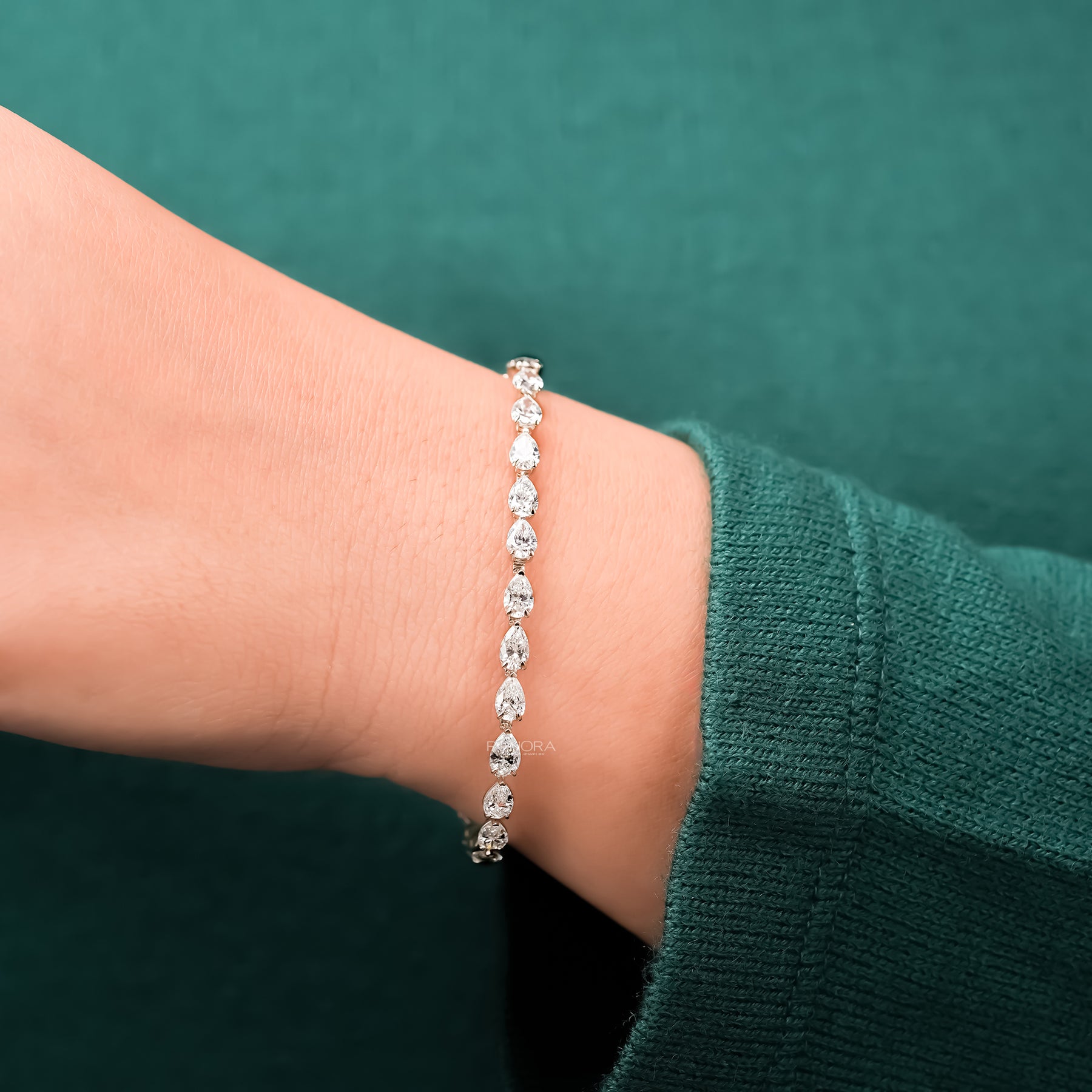 Pear lab grown diamond tennis bracelet worn with green sleeve