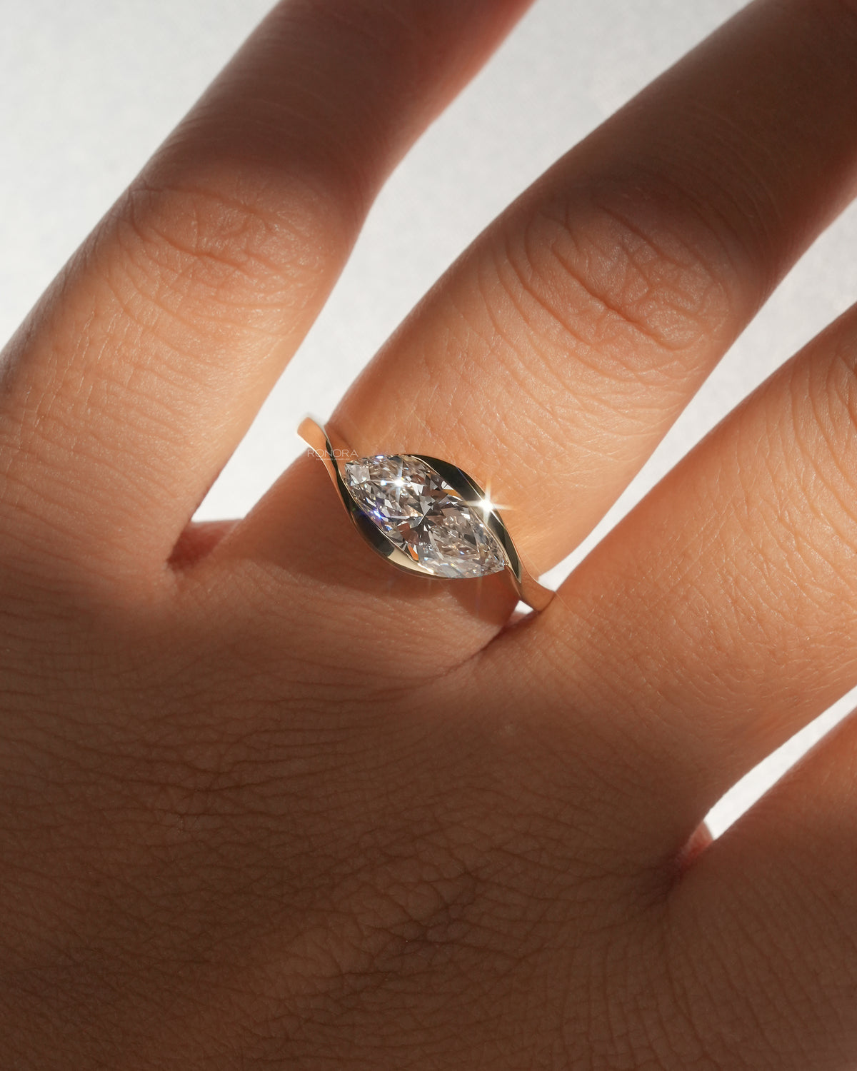 Marquise bezel lab grown diamond ring worn on hand showing the east west setting