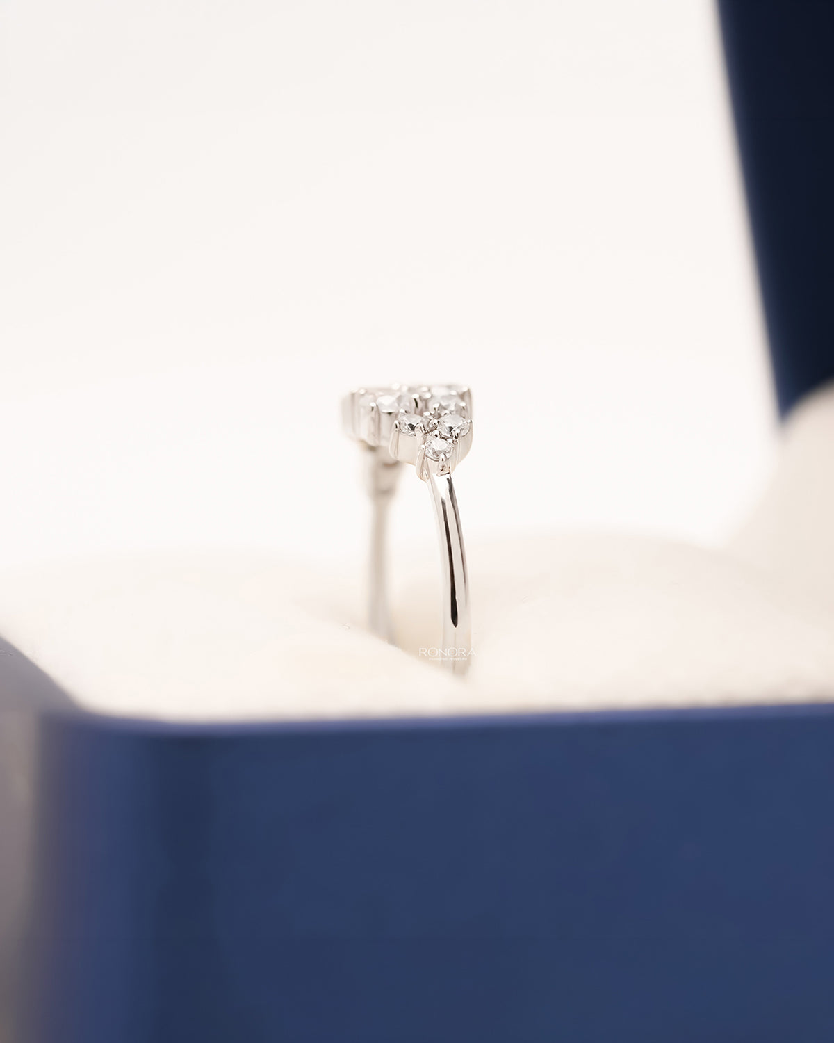 Side profile of white metal lab grown diamond cluster ring showing raised setting
