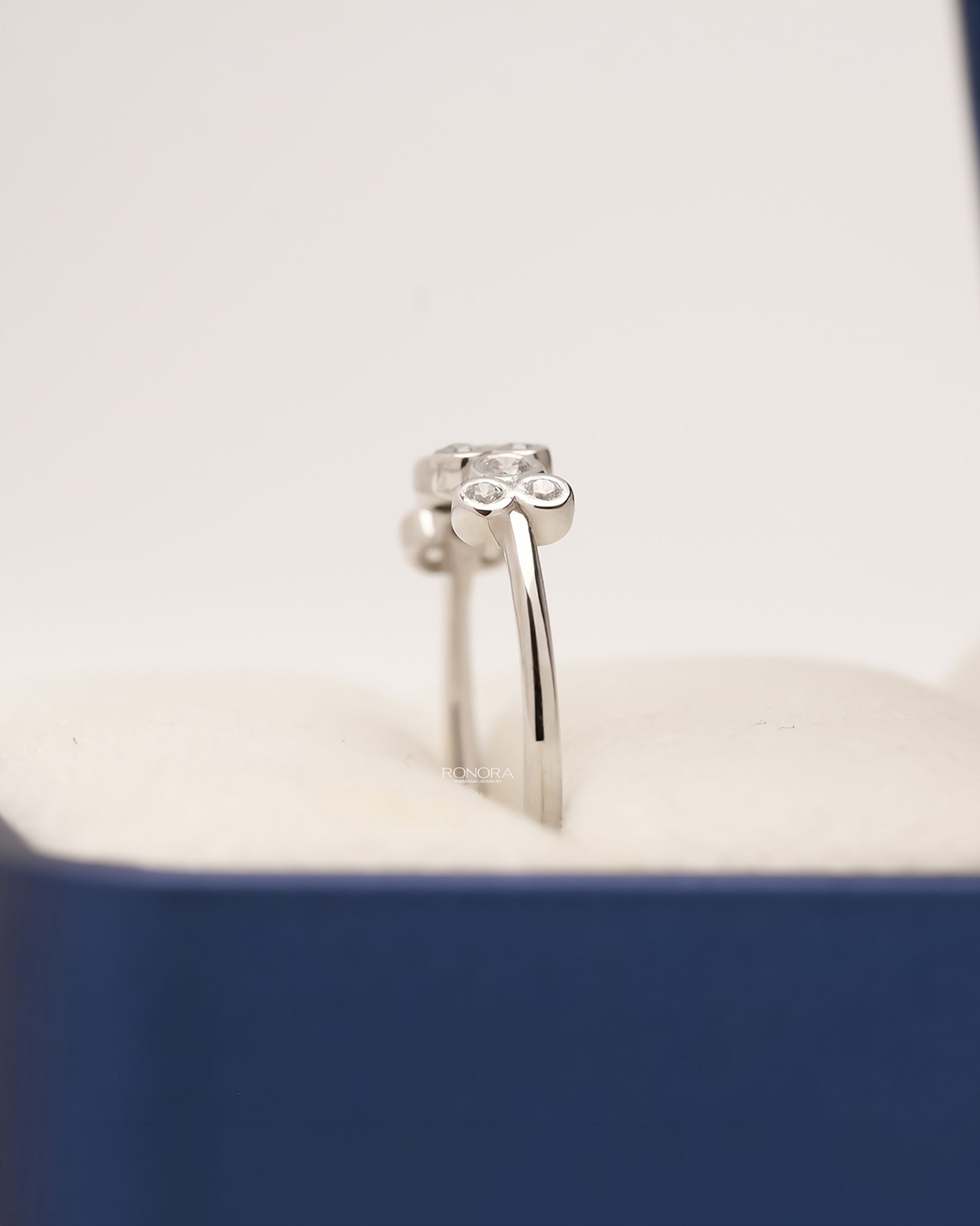 Side profile of white metal five-stone lab grown diamond band showing raised setting