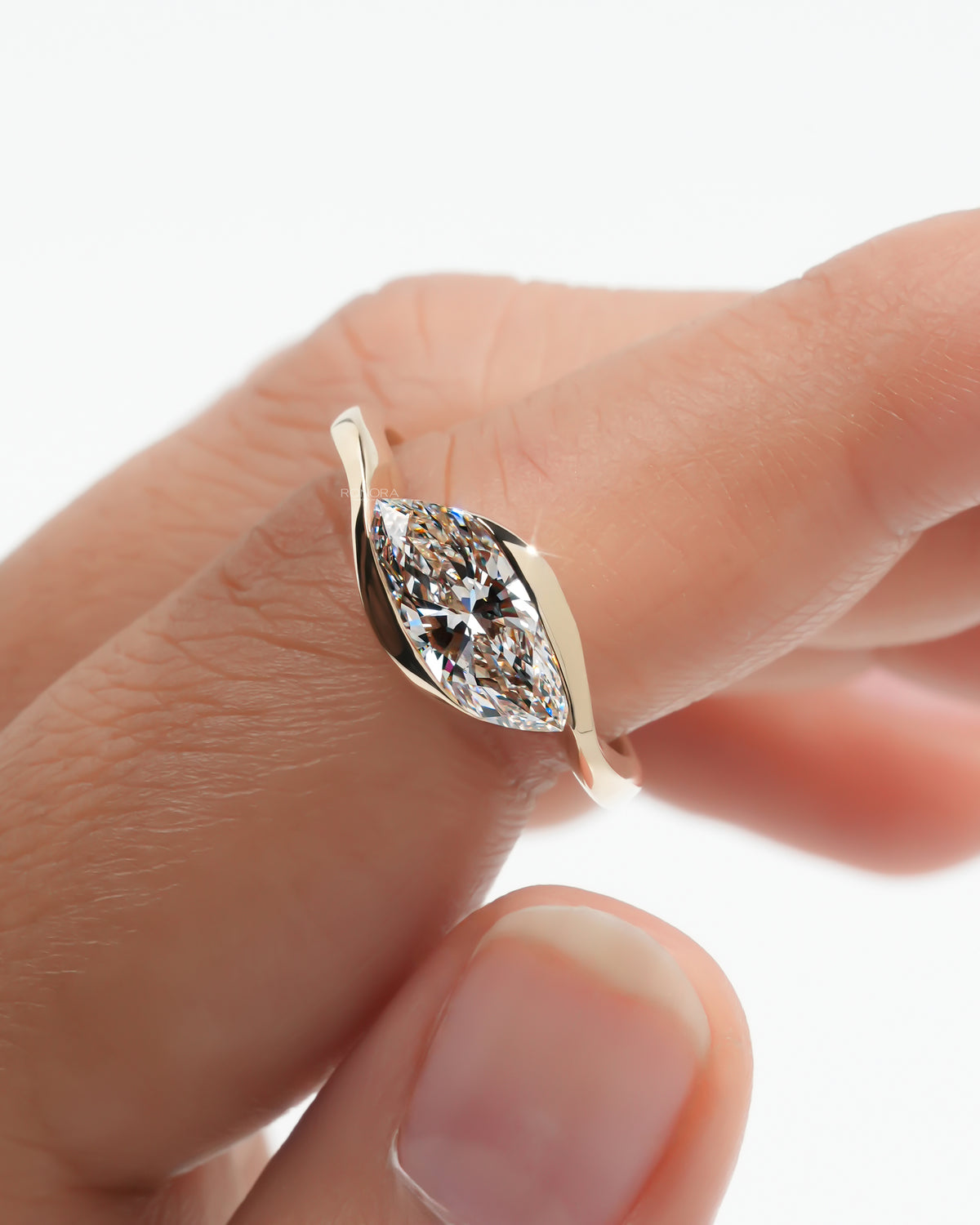 Close-up of the marquise bezel lab grown diamond ring held between fingertips