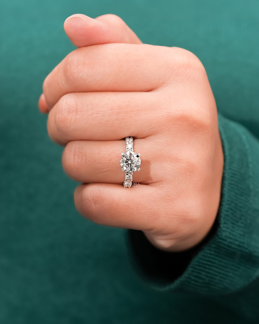 round lab grown diamond side-stone ring worn on hand in white gold