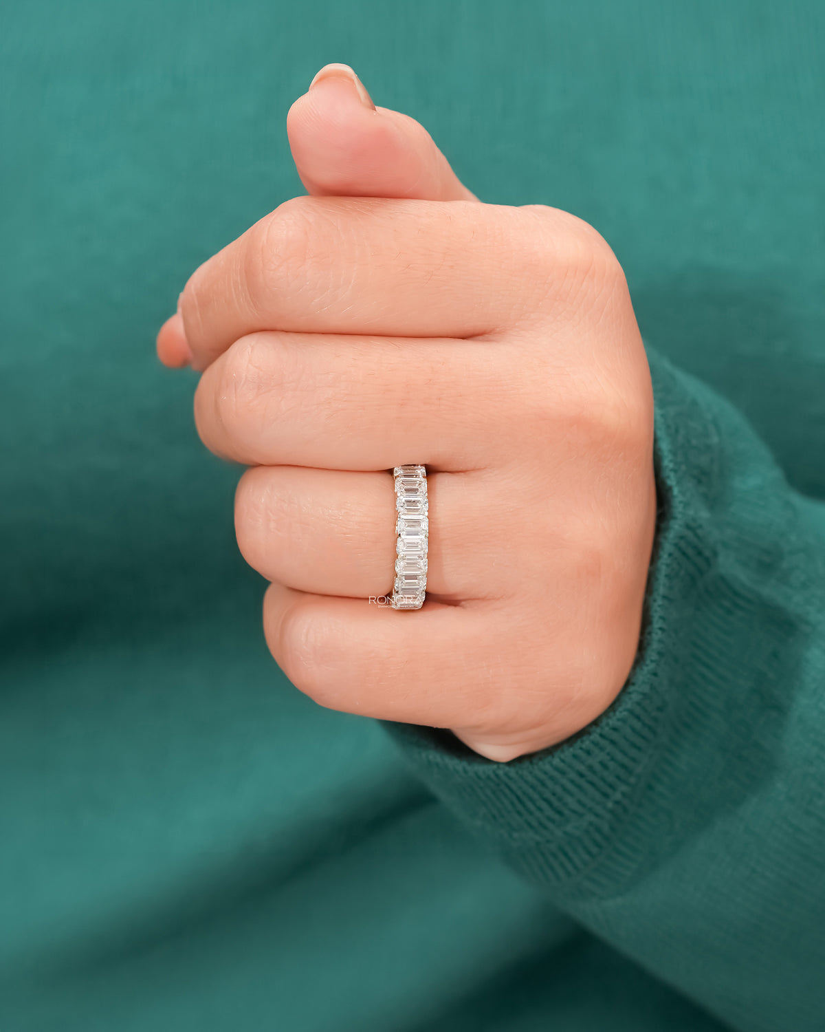 emerald lab grown diamond eternity band worn on hand in white gold
