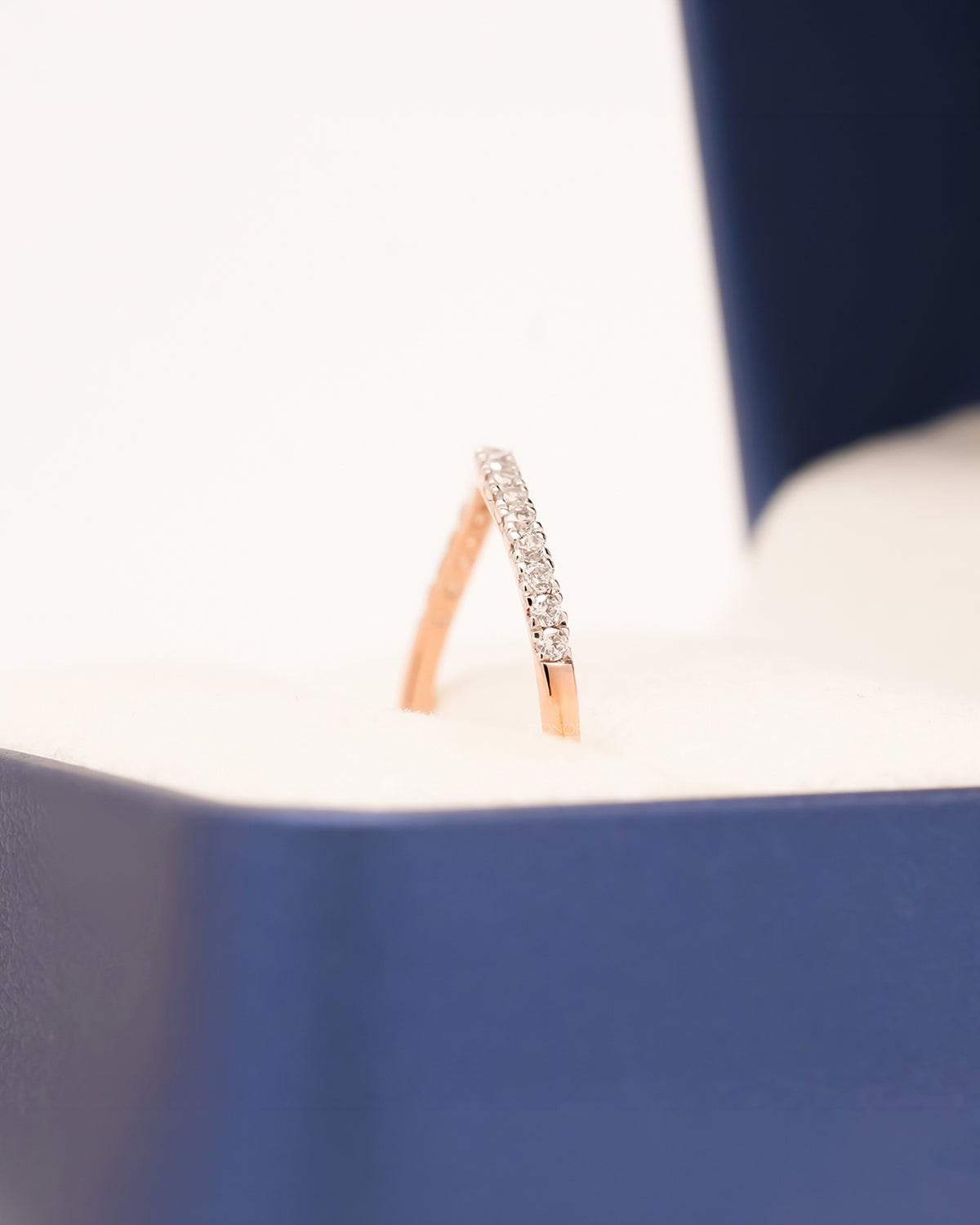 Side profile of rose gold curved pavé band showing diamond arc