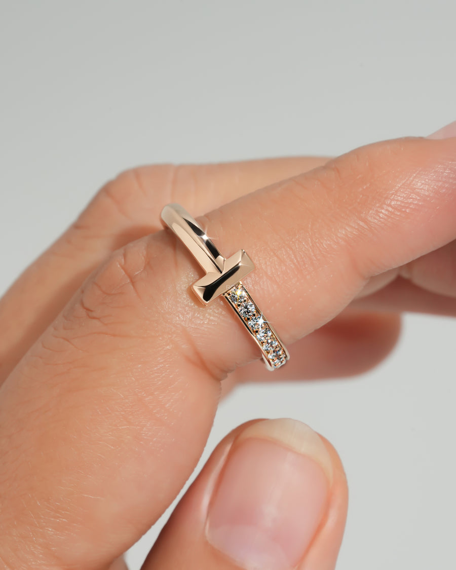 Rose gold flat bar lab grown diamond ring with a dainty pave band, held between two fingers, close-up
