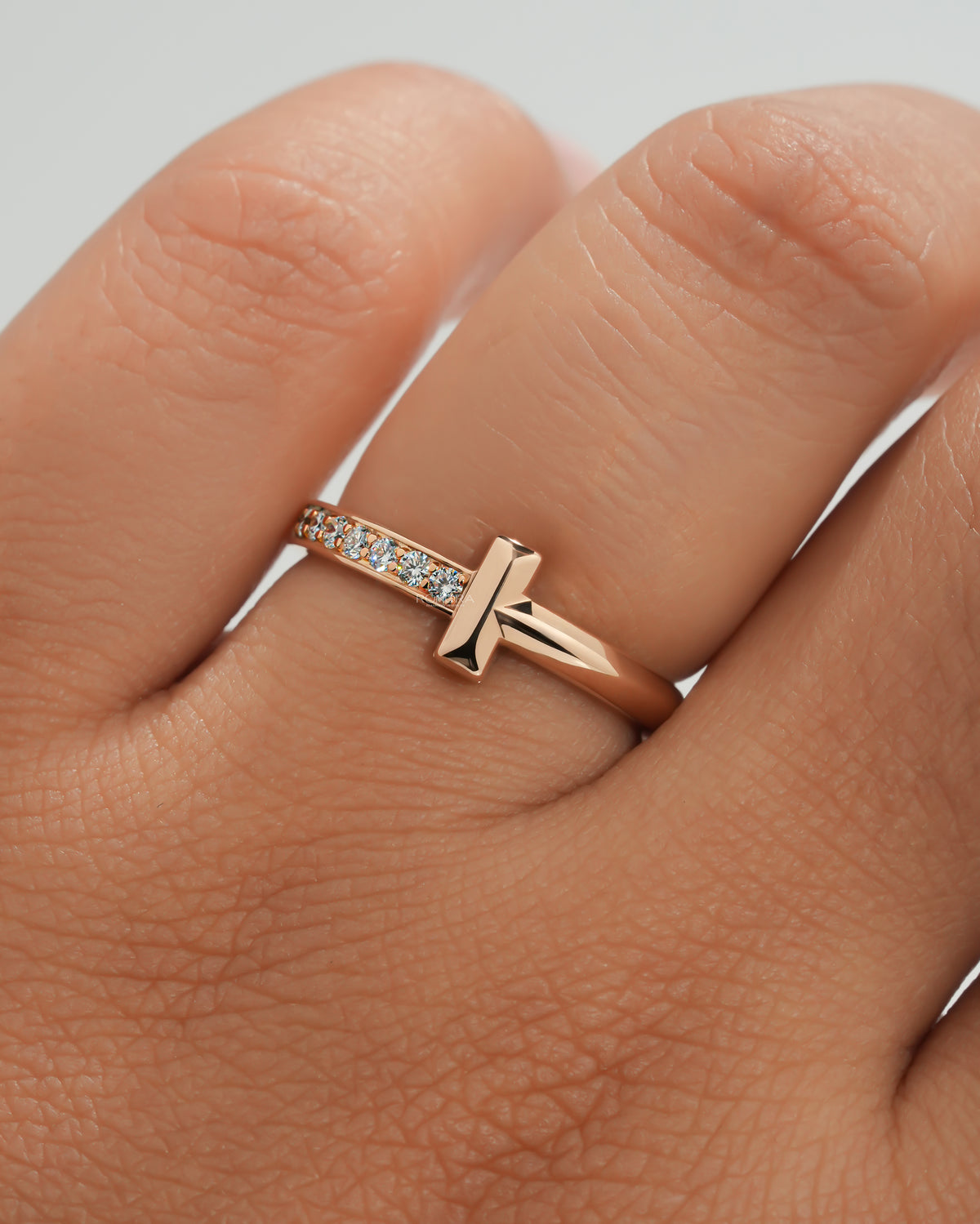 Rose gold flat bar lab grown diamond ring with a dainty pave band worn on a finger, close-up on the hand