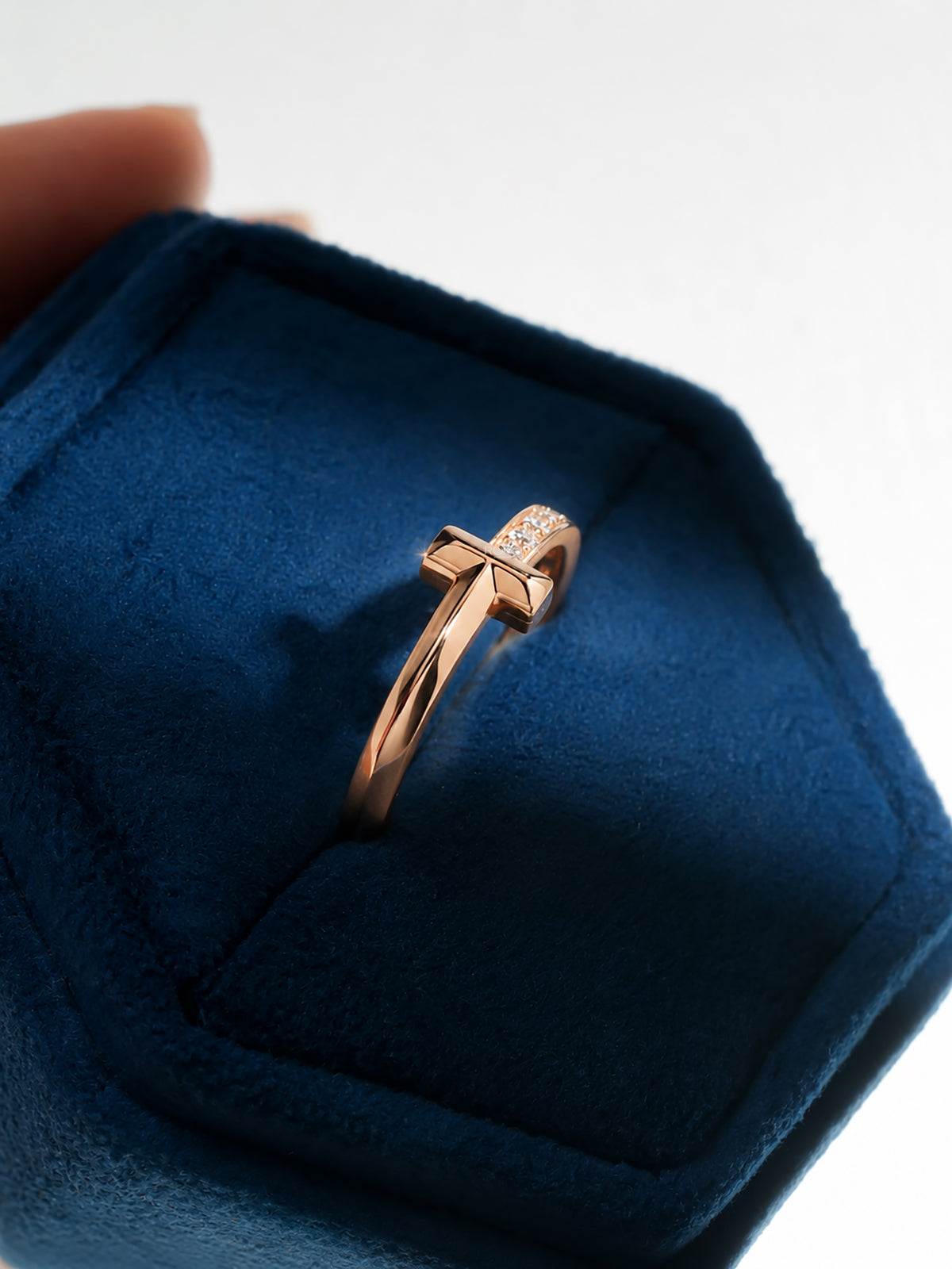 Angle view of a flat bar lab grown diamond ring in rose gold with a pave band, in a blue velvet ring box