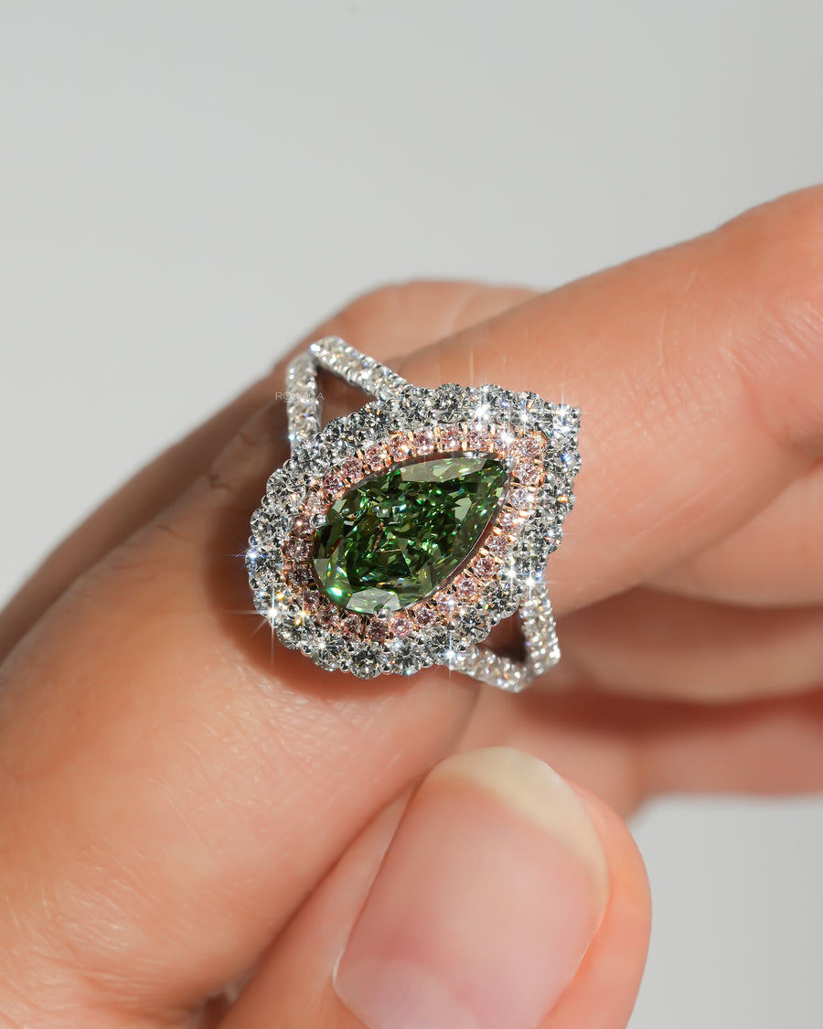 Pear green lab grown diamond ring with a pink and white double halo, held between fingers, close-up