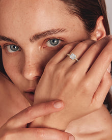 Model wearing an asscher pave lab grown diamond ring in yellow gold, hand raised close to her face