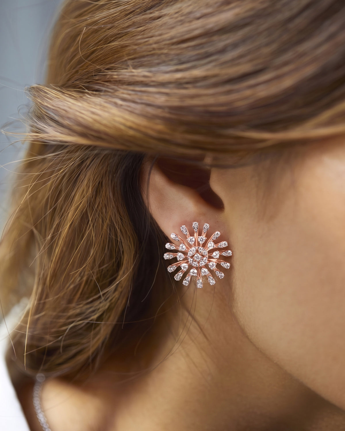 Model wearing a starburst cluster lab grown diamond earring in rose gold, side profile close-up