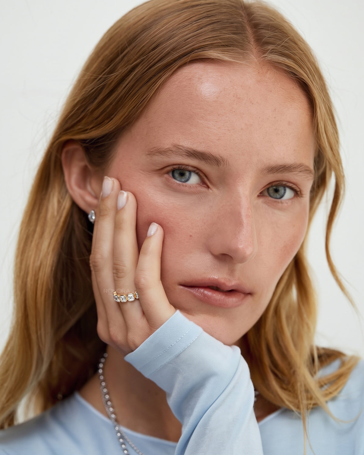 Model resting her cheek on her hand wearing an asscher cut lab grown diamond eternity band with bezel set stones