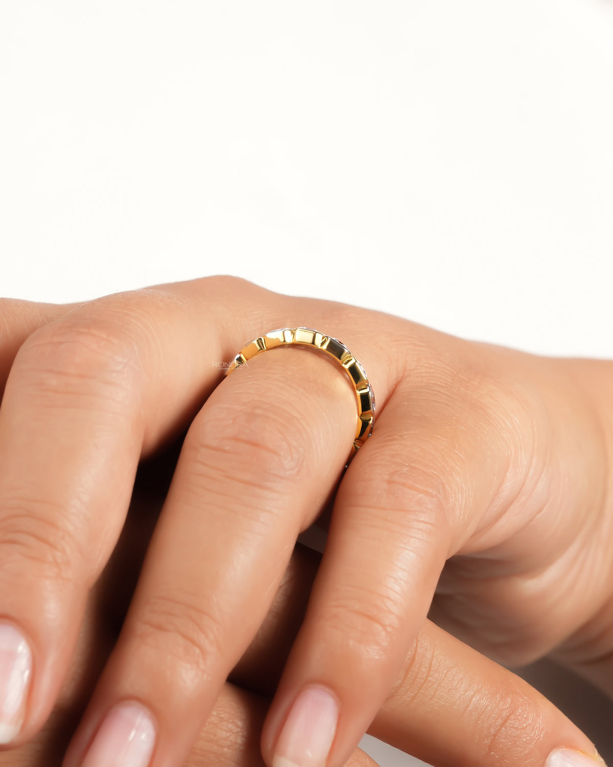 Side view of a yellow gold asscher cut lab grown diamond eternity band on a finger showing the bezel set shank