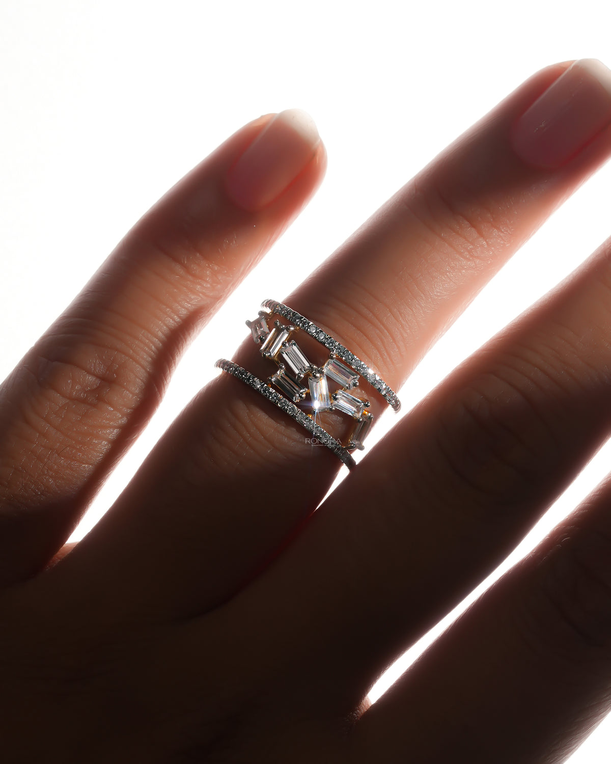 Hand wearing a baguette lab grown diamond cluster ring with scattered baguette stones between two pave rows