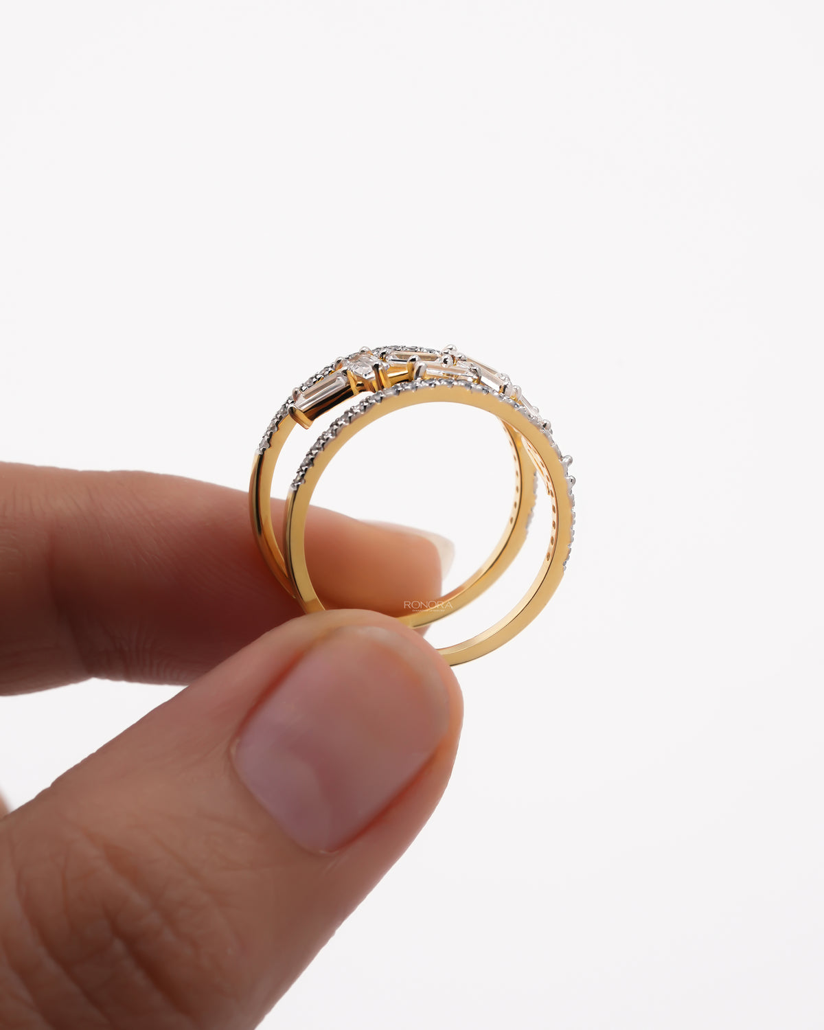Side profile of a yellow gold baguette lab grown diamond cluster ring held between fingers, double pave band