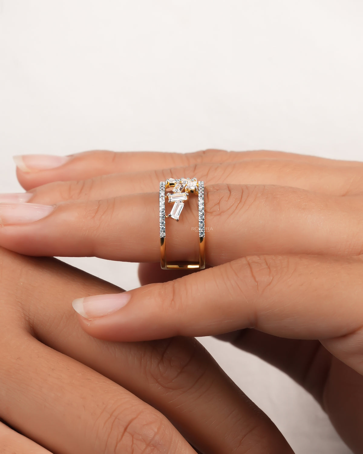 Side view of a baguette lab grown diamond cluster ring on a finger, yellow gold open band and pave edges
