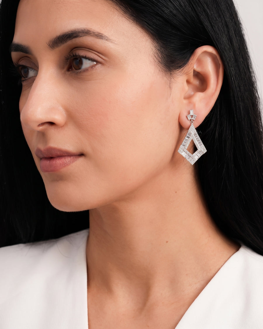 Woman in profile wearing baguette lab grown diamond drop earrings with an open kite shaped drop in white gold