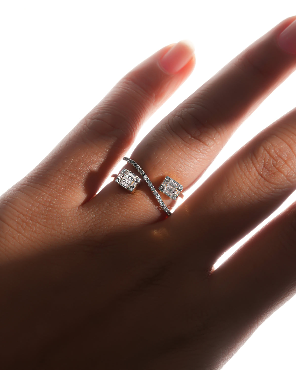 Hand wearing a baguette lab grown diamond toi et moi ring with two baguette clusters and a curved pave bar