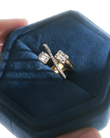 Baguette lab grown diamond toi et moi ring with a yellow gold band in a blue velvet ring box held in hand