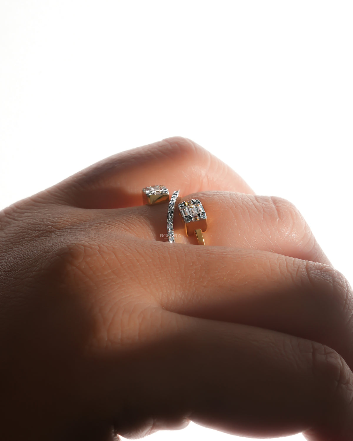 Low angle view of a baguette lab grown diamond toi et moi ring on a finger, yellow gold band with pave bar
