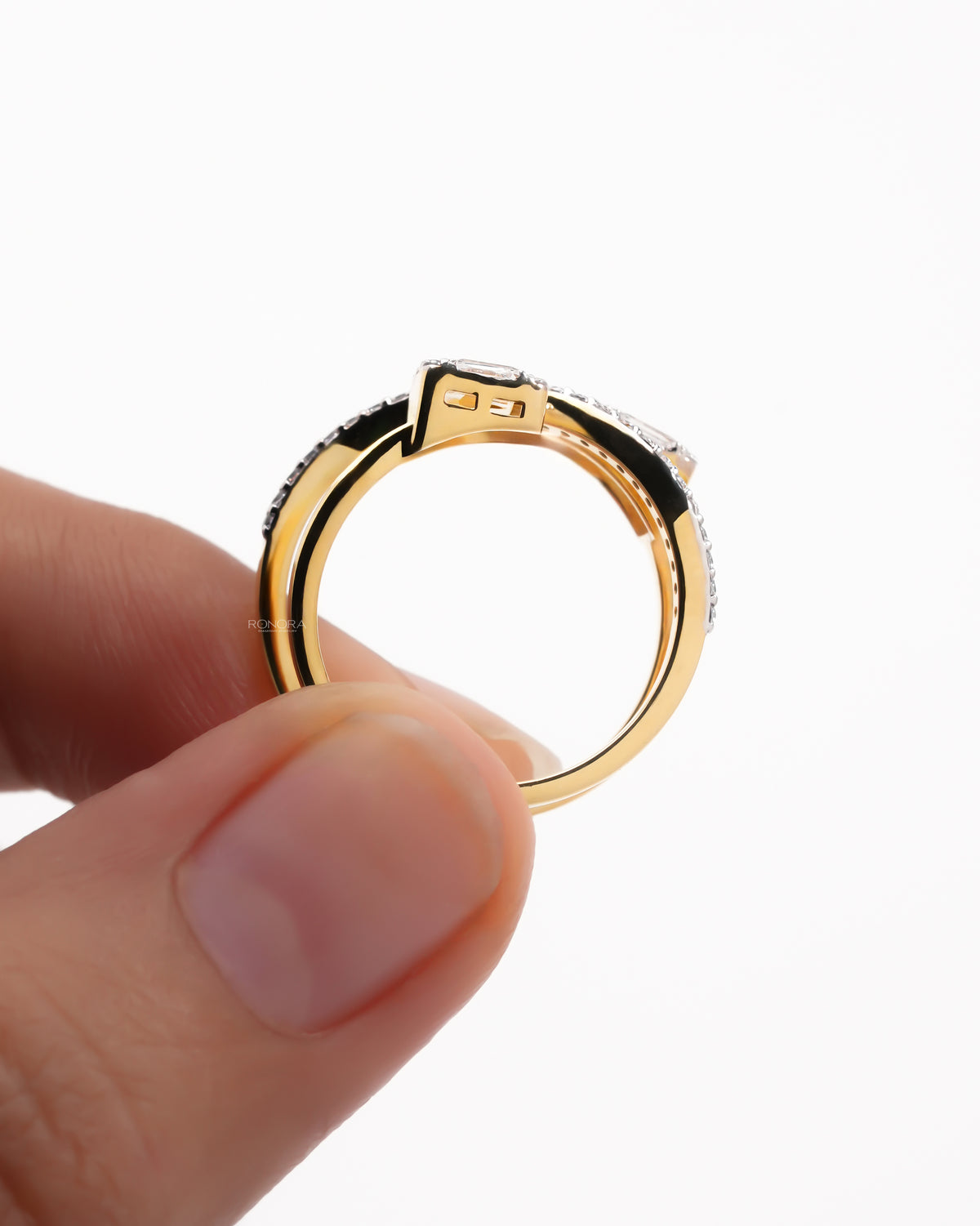Side view of a yellow gold baguette lab grown diamond toi et moi ring held between two fingers