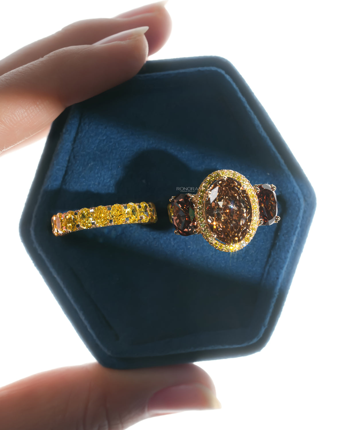 Top view of a brown oval lab grown diamond bridal set in a blue velvet ring box, ring and band side by side