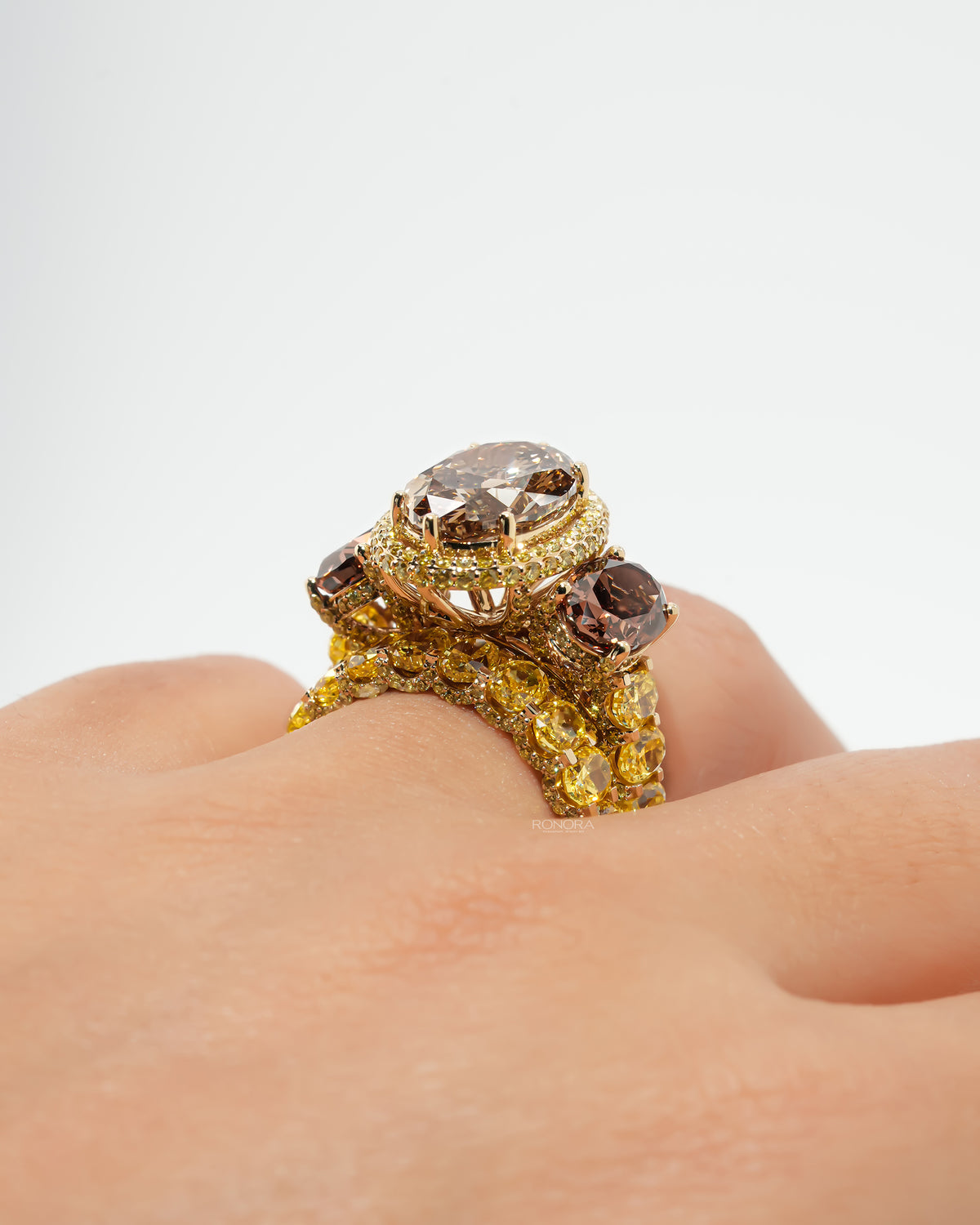 Brown oval lab grown diamond bridal set worn on a hand, side angle of the halo ring stacked on a yellow oval band