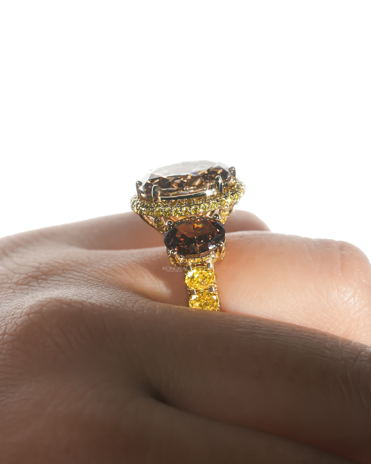 Side profile of a brown oval lab grown diamond three stone ring on a finger, with yellow oval stones along the band