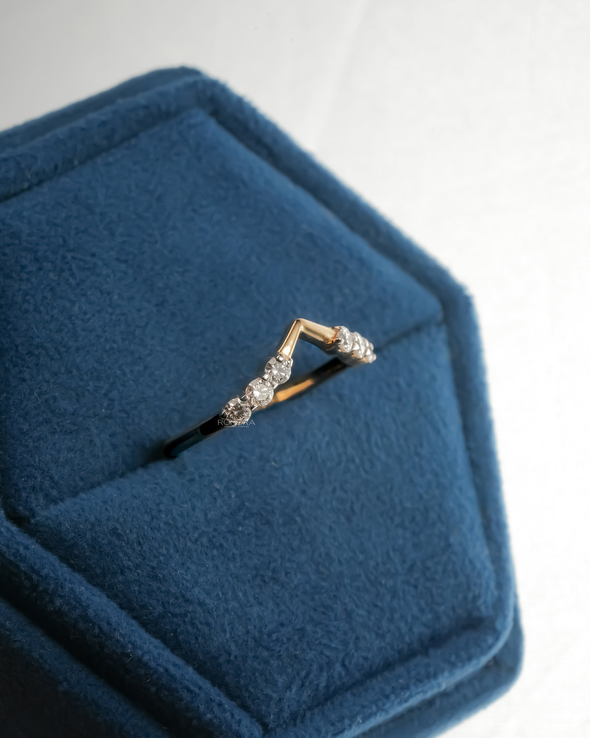 Chevron lab grown diamond wedding band resting on blue velvet, showing the V shaped gold band and round stones