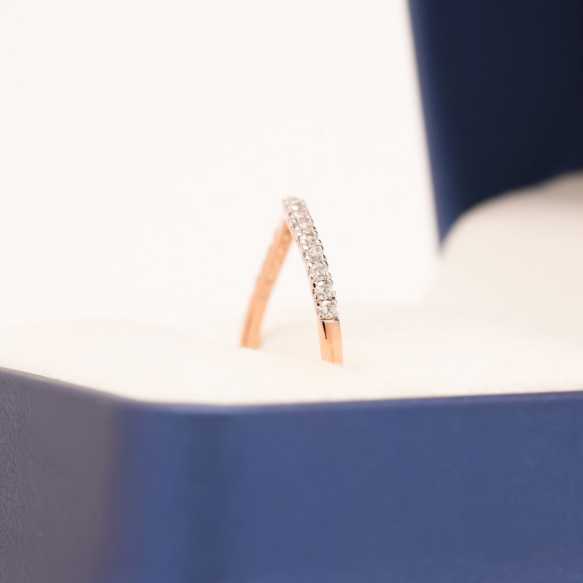 Curved pave lab grown diamond wedding band in rose gold, side view showing the row of small stones in a blue ring box