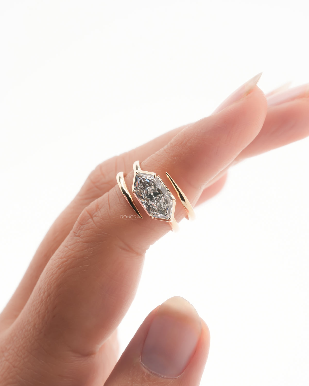 Close-up of a Dutch marquise lab grown diamond ring in rose gold worn on a finger with a bypass band