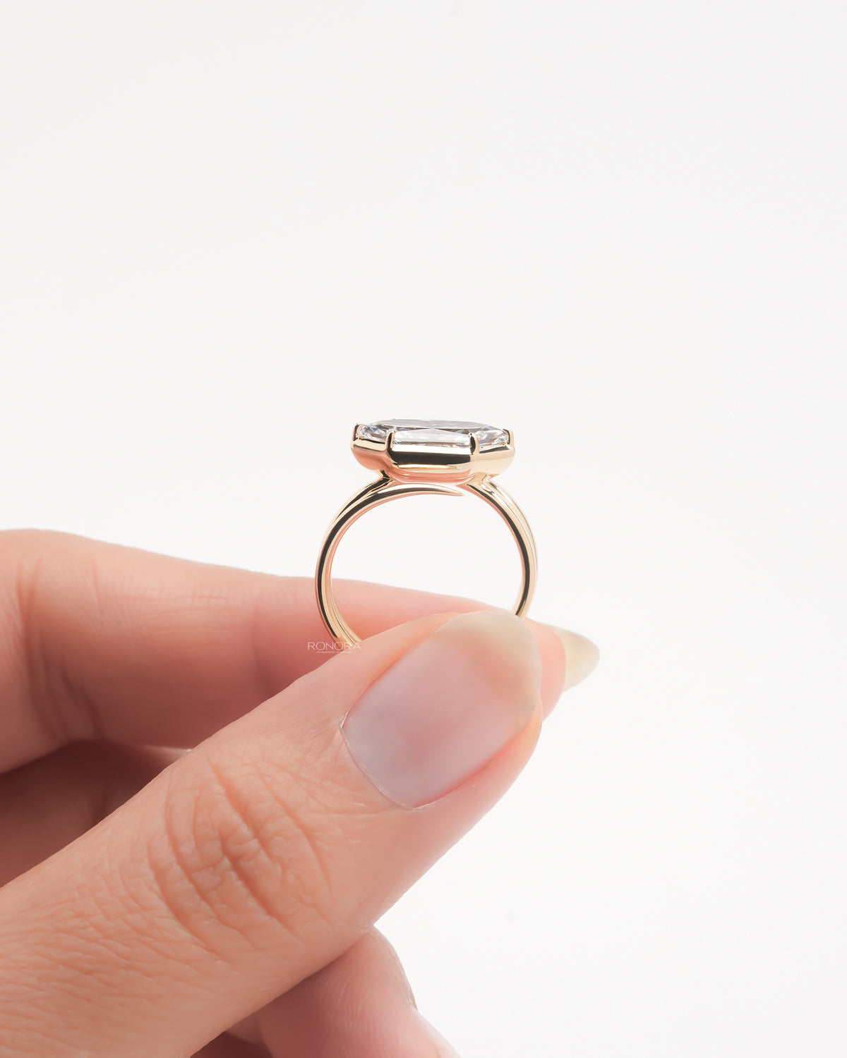 Dutch marquise lab grown diamond ring held between fingers showing the rose gold bezel and bypass band profile