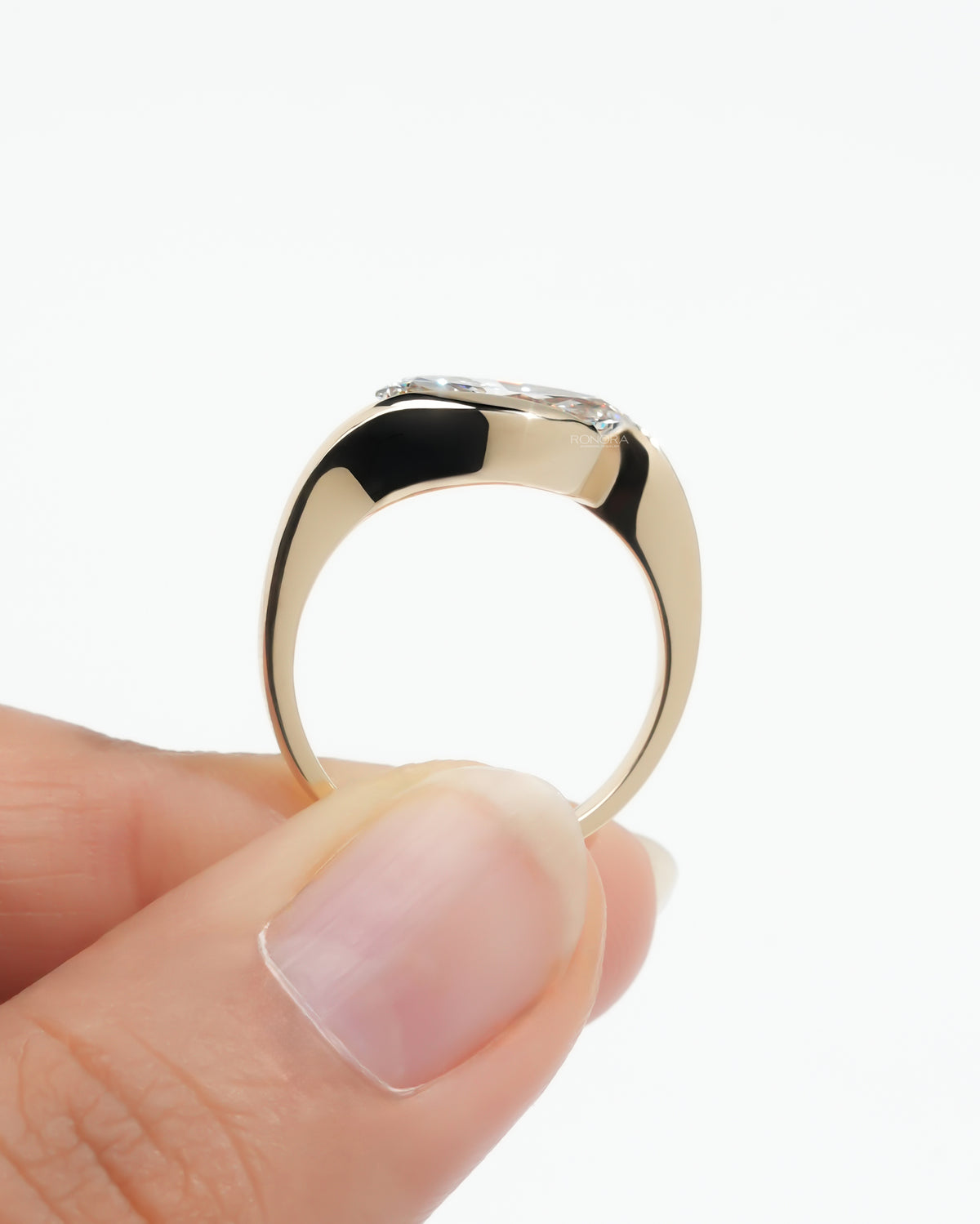 Marquise bezel lab grown diamond ring held up to show the yellow gold band profile