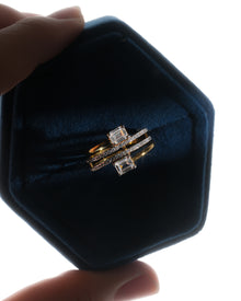 Emerald cut toi et moi lab grown diamond ring in a blue velvet hexagon ring box, yellow gold wrap band, top view