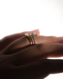 Emerald cut toi et moi lab grown diamond ring in yellow gold worn on a finger, side view in soft backlight