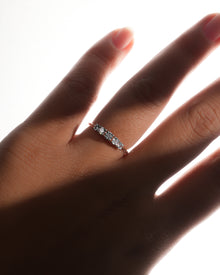 Five stone lab grown diamond pinky ring with graduated round stones, worn on a hand in soft backlight