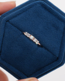 Top view of a rose gold five stone lab grown diamond pinky ring with round stones in a blue velvet ring box