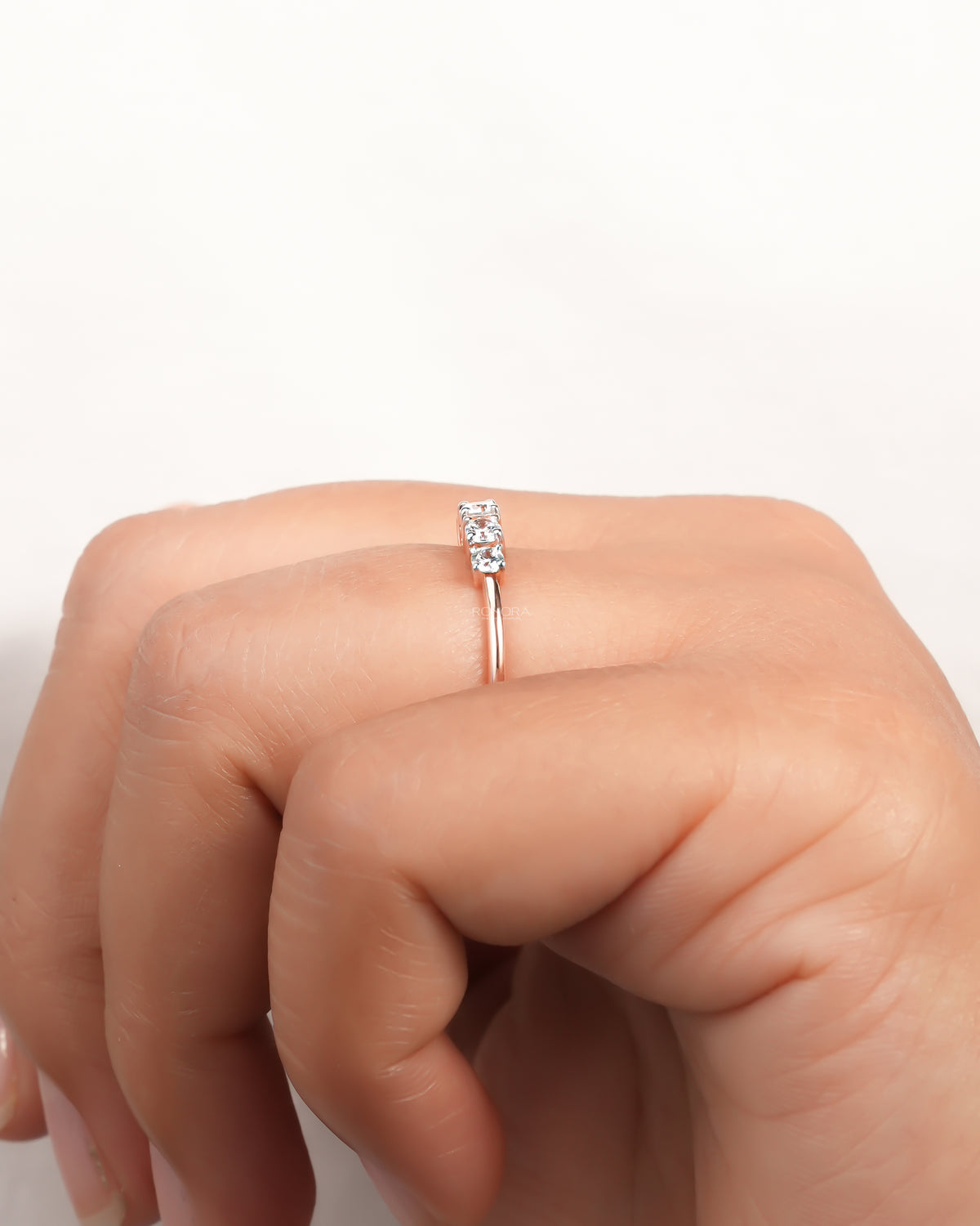 Side view of a rose gold five stone lab grown diamond pinky ring on a finger with a slim dainty band