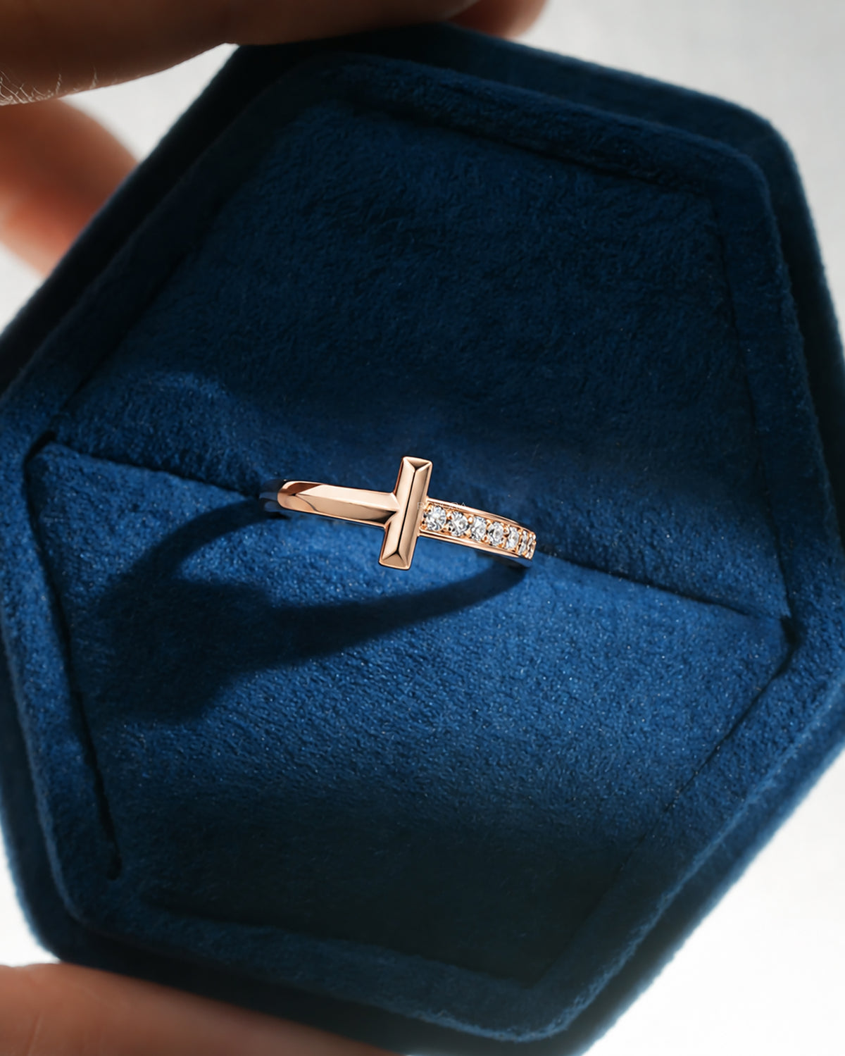 Front view of a rose gold flat bar lab grown diamond ring with pave band in a blue velvet hexagonal ring box