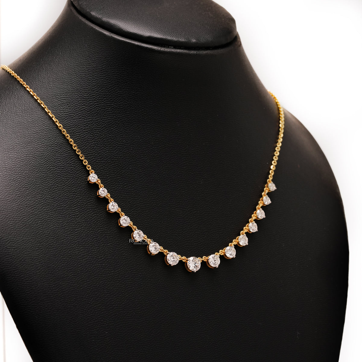 Round lab grown diamond tennis necklace in yellow gold on a black display bust, angled view of the graduated stones