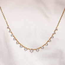 Round lab grown diamond tennis necklace in yellow gold with graduated stones against a soft cream background