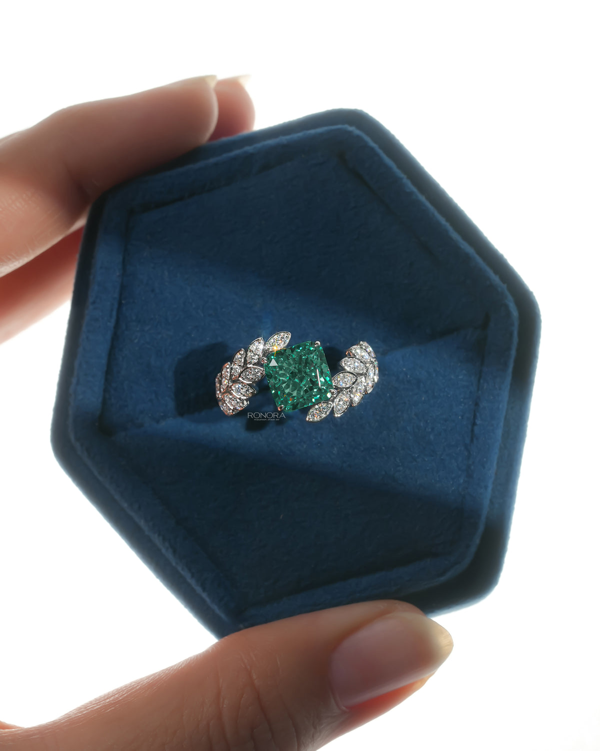 Green cushion lab grown diamond engagement ring in white gold in a blue velvet ring box, top view