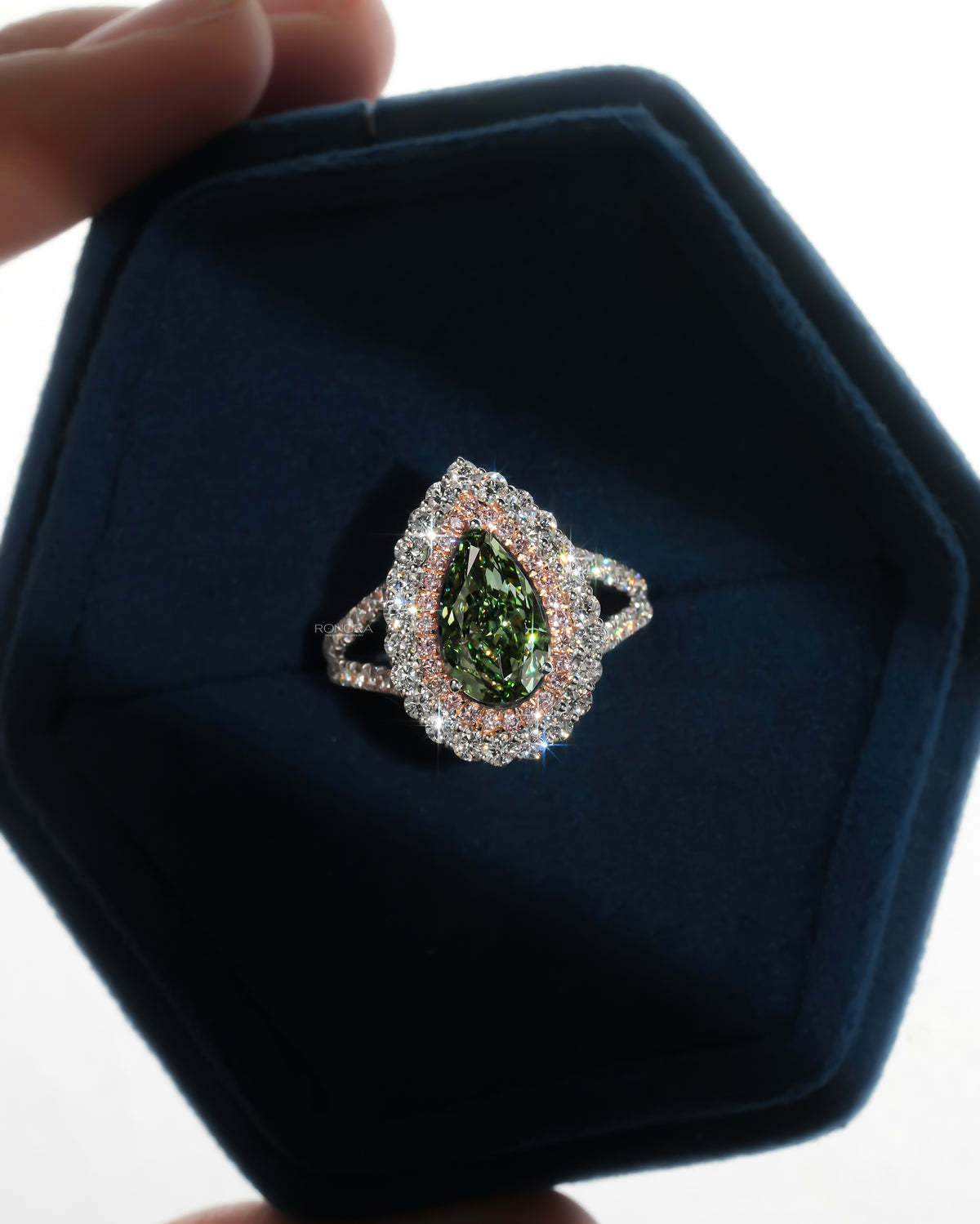 Pear green lab grown diamond ring with pink double halo, top view in a blue velvet hexagon ring box
