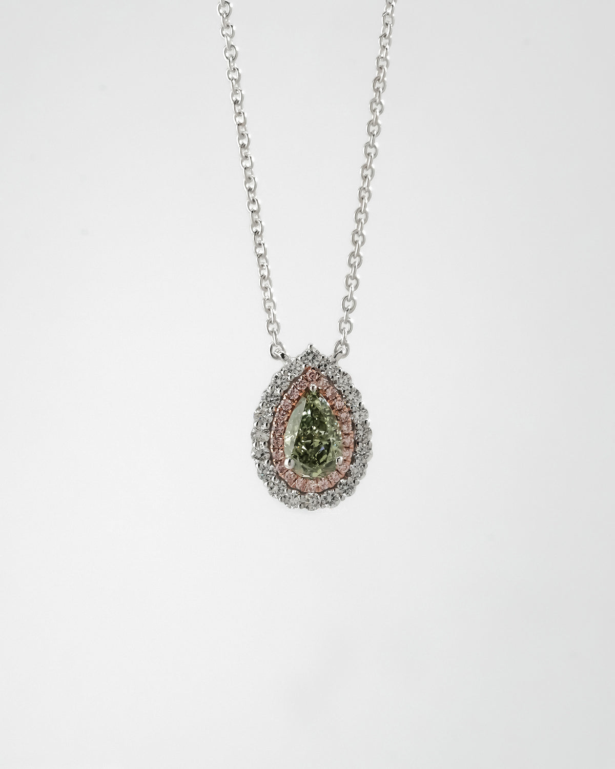 Green pear lab grown diamond pendant hanging on a white gold chain, pink and white double halo, plain background