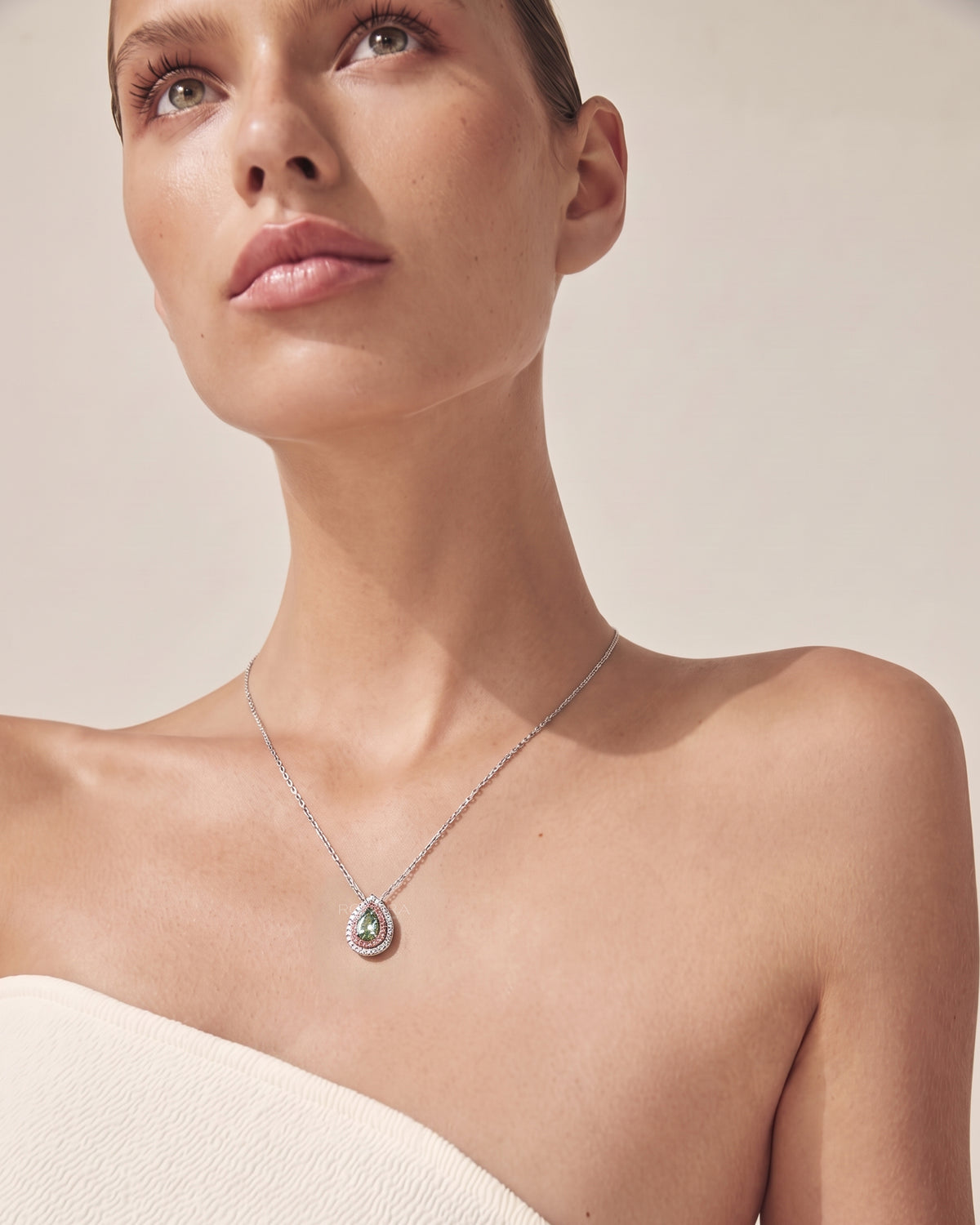 Model wearing a green pear lab grown diamond pendant with a pink double halo on a fine white gold chain