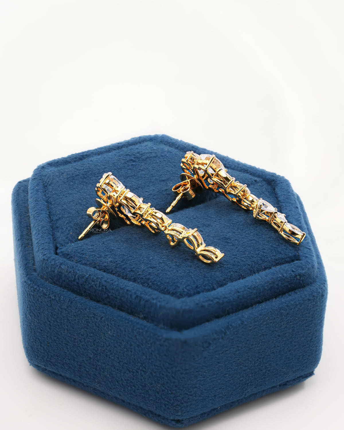 Back view of heart lab grown diamond drop earrings in yellow gold showing the posts and backs on a blue velvet box