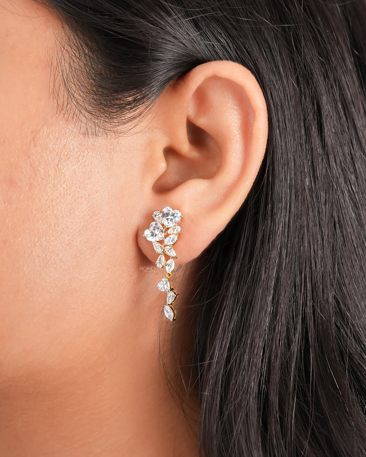 Close-up of an ear wearing a heart lab grown diamond drop earring with a yellow gold cluster cascade of stones