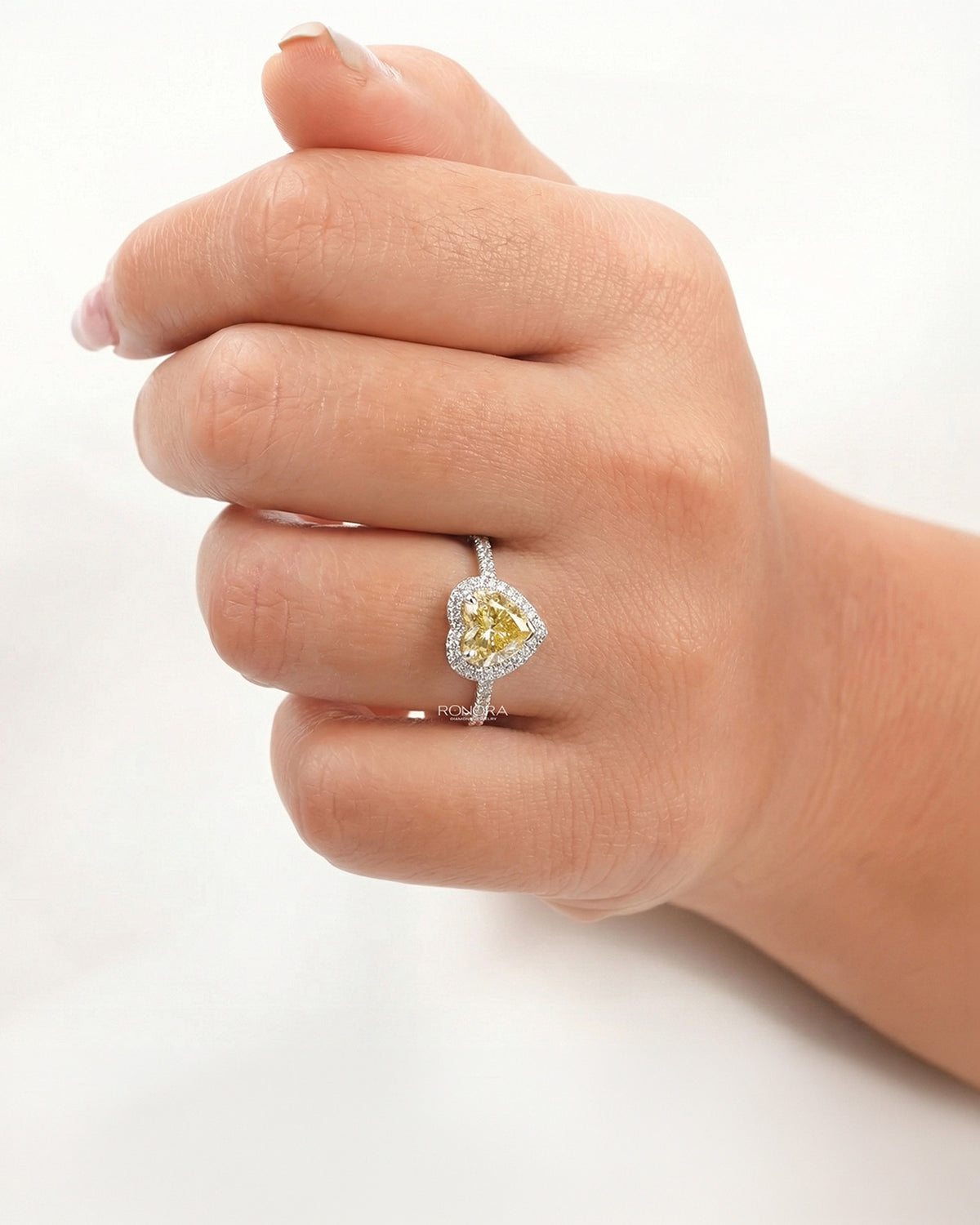 yellow heart lab grown diamond halo ring worn on hand in white gold