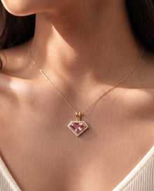 Woman wearing a pink shield cut lab grown diamond necklace with a halo on a fine yellow gold chain, close-up