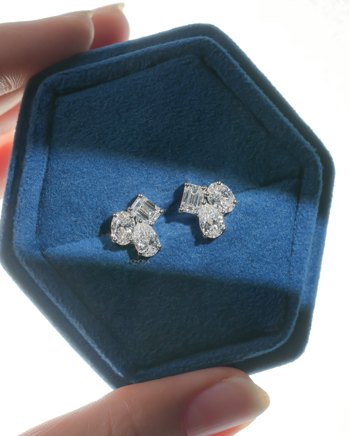 Pair of lab grown diamond cluster stud earrings with emerald, pear and oval stones in a blue velvet hexagon box
