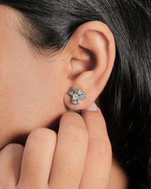 Close-up of an ear wearing lab grown diamond cluster stud earrings with emerald, pear and oval cut stones